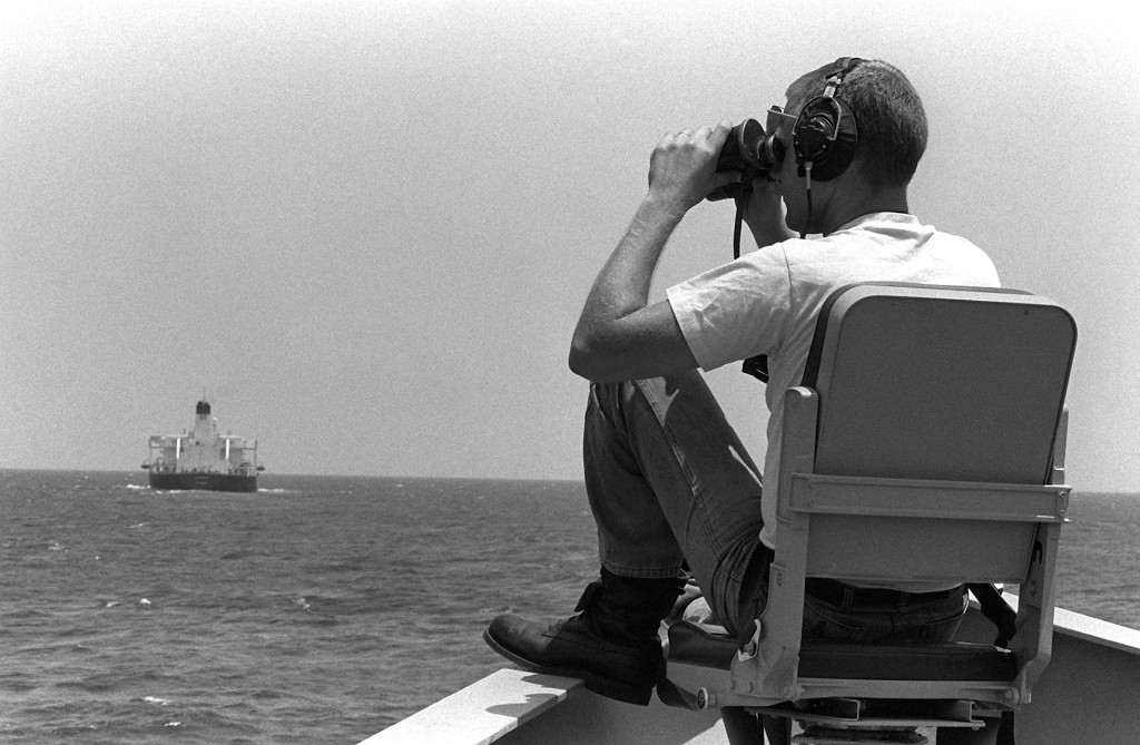 Mess Management Specialist 2nd Class Williams Hendrickson scans for mines from the bow of the guided missile frigate USS Nicholas (FFG-47) on June 1, 1988, during an Earnest Will convoy. (PHCS Mitchell/U.S. Navy)
