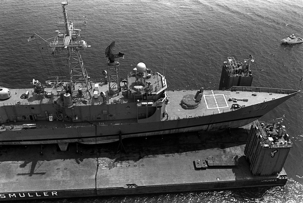 A Coast Guard boat, upper right, guards the <i>Roberts</i> and the MS2 in the harbor. (PH2 Elliott/U.S. Navy)