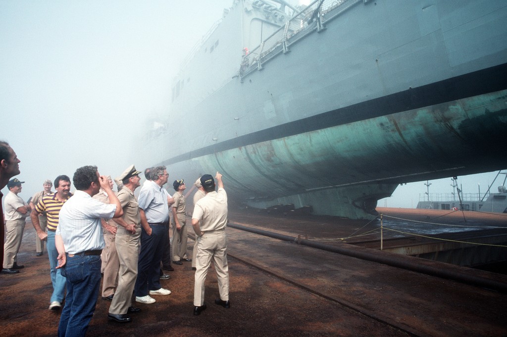 A crowd observes the damaged guided missile frigate USS SAMUEL B. ROBERTS (FFG-58) secured on the deck of the Dutch salvage ship MIGHTY SERVANT II. The MIGHTY SERVANT II transported the frigate back to its home port after it struck a mine in the Persian Gulf on 14 April 1988.